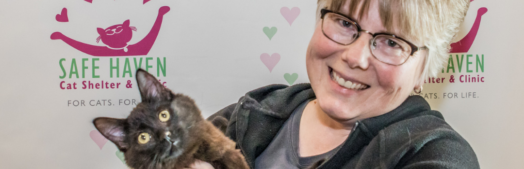 Blonde Woman With Newly Adopted Black Cat Both Looking at Camera